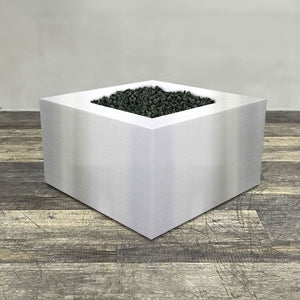 A side view of the 36" Square Gravity Stainless Steel Fire Pit by Starfire Designs - perfect for outdoor patio spaces. Natural gas or propane compatible, enhancing warmth and ambiance. Lava rocks included for added aesthetic.