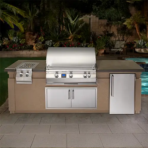 A complete outdoor kitchen island is on display in front of a pool with a tropical theme