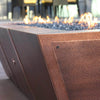10ft Copper Spartan Gas Fire Pit with flames reflecting off fire glass, creating an elegant outdoor centerpiece