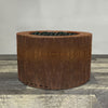 A side view of the 36" Round Gravity Corten Steel Fire Pit by Starfire Designs - perfect for outdoor patio spaces. Natural gas or propane compatible, enhancing warmth and ambiance. Lava rocks included for added aesthetic.