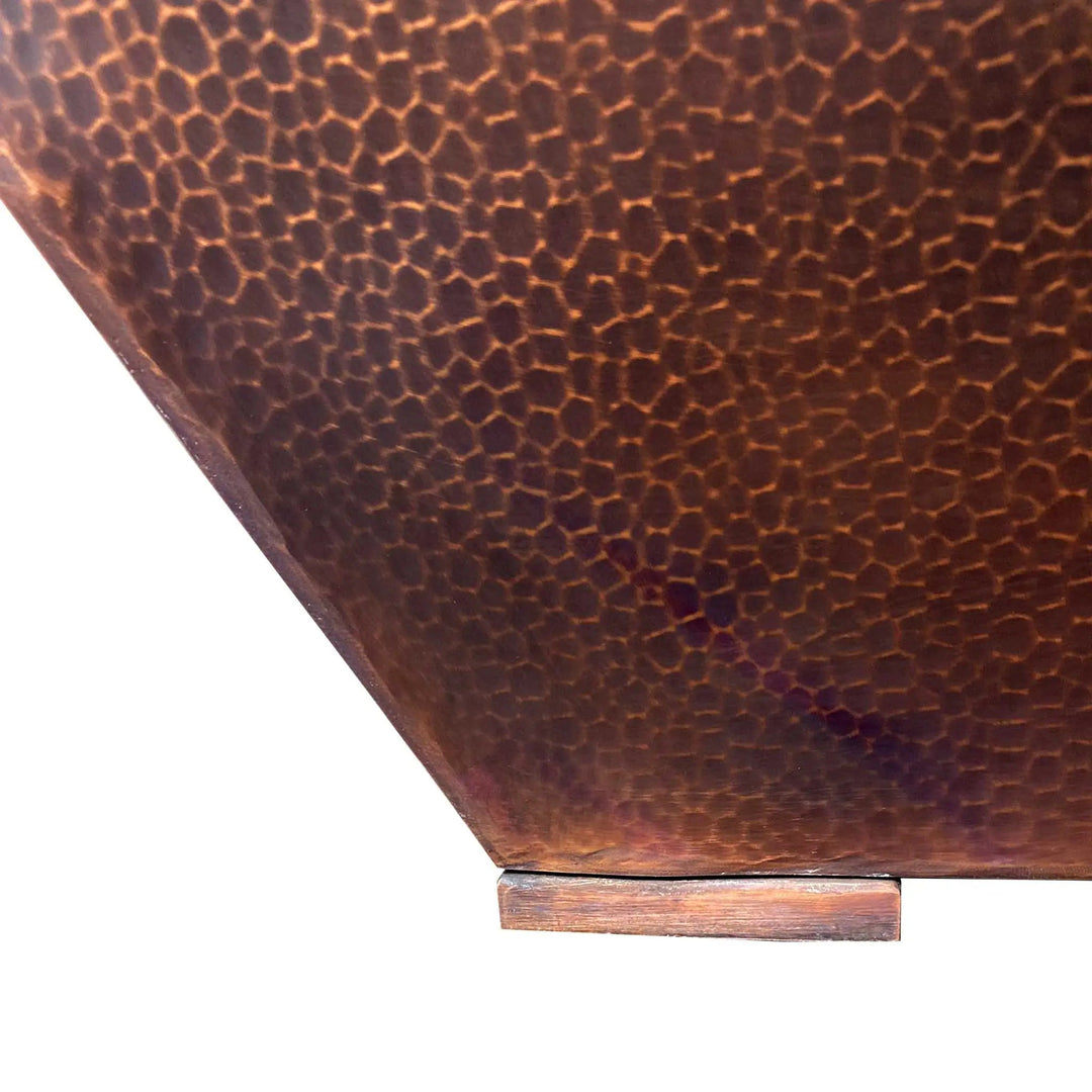 Close-up view of the hand-hammered copper texture and base of the Plaza Moreno 40" square fire pit, highlighting the craftsmanship and sturdy construction of this modern outdoor fire pit by Starfire Designs