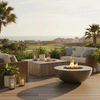 A sunny wooden deck overlooks a golf course and ocean horizon, featuring a brown luxury fire pit as the focal point. Wicker furniture and tropical plants surround the round fire pit, creating a relaxing family gathering fire pit area. The bright flames of the outdoor fire pit blend with the natural daylight, illustrating the versatility of a propane fire pit in a coastal resort setting.