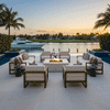 A white square fire feature sits on a tiled terrace overlooking a marina with docked yachts at sunset. Surrounded by a large sectional sofa and armchairs, the propane fire pit creates an inviting atmosphere for evening relaxation. The clean burn demonstrates a smokeless fire pit experience, enhancing the cozy backyard fire pit ambiance in a luxurious coastal setting.