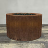 A side view of the 45" Round Gravity Corten Steel Fire Pit by Starfire Designs - perfect for outdoor patio spaces. Natural gas or propane compatible, enhancing warmth and ambiance. Lava rocks included for added aesthetic.