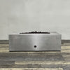 A side view of the 48" x 24" Rectangle Gravity Powder Coated Steel Fire Pit - Propane Gas Hardline - Push Button Spark Ignition - Silver Hammertone by Starfire Designs - perfect for outdoor patio spaces. Natural gas or propane compatible, enhancing warmth and ambiance. Lava rocks included for added aesthetic.