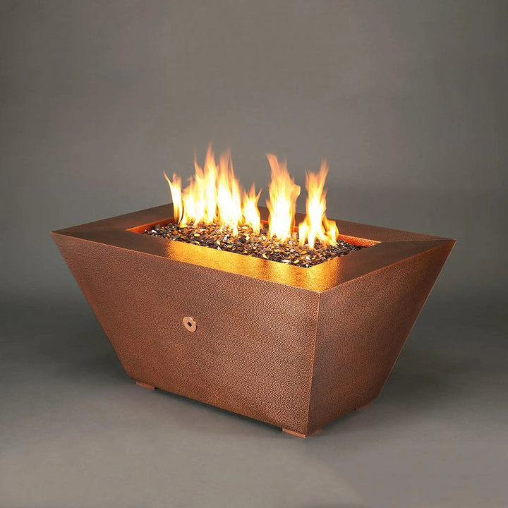 48" x 32" Copper Canyon gas fire pit by Starfire Designs, enhancing an outdoor patio setting, with a hammered copper finish, perfect for luxurious outdoor living spaces