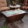 Close-up of the 48" x 32" Copper Canyon gas fire pit by Starfire Designs in an outdoor patio setting, featuring a hammered copper finish, perfect for creating a warm, inviting ambiance in outdoor spaces
