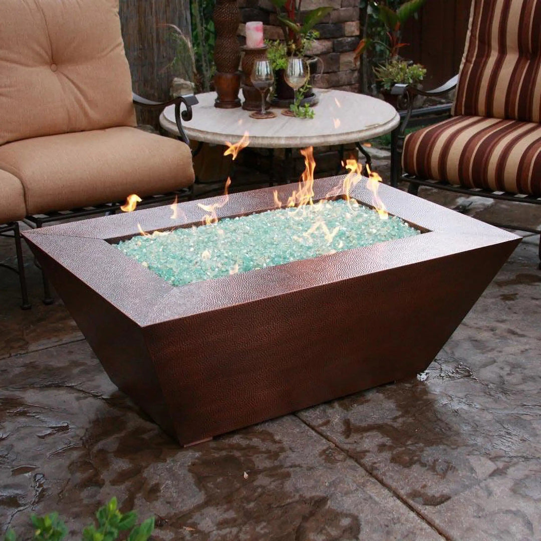 Close-up of the 48" x 32" Copper Canyon gas fire pit by Starfire Designs in an outdoor patio setting, featuring a hammered copper finish, perfect for creating a warm, inviting ambiance in outdoor spaces