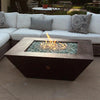 50-inch Plaza Moreno copper fire pit with blue fire glass and flames, set in an elegant patio, ideal for luxury outdoor fire pit experiences by Starfire Designs