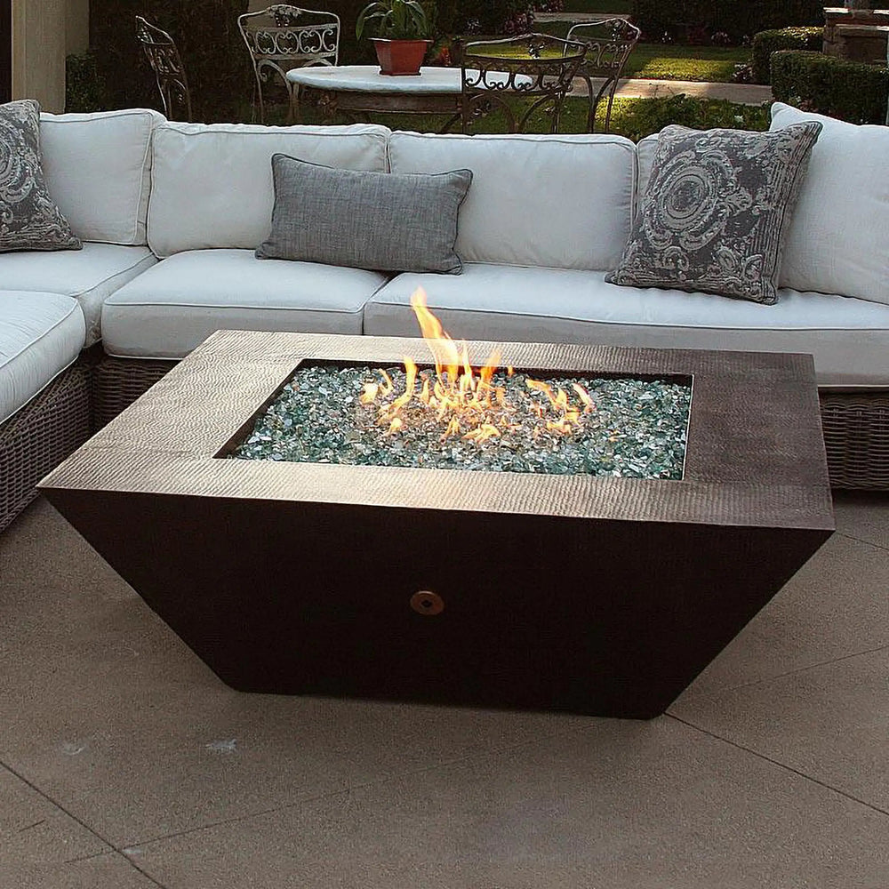 50-inch Plaza Moreno copper fire pit with blue fire glass and flames, set in an elegant patio, ideal for luxury outdoor fire pit experiences by Starfire Designs