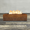 Front view of 60" x 24" Rectangle Gravity Corten Steel Fire Pit by Starfire Designs - Brown with flames on, featuring sleek modern design and durable construction, perfect for outdoor patio spaces. Natural gas or propane compatible, enhancing warmth and ambiance. Lava rocks included for added aesthetic.