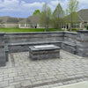 Modern outdoor patio with built-in stone seating and a central fire feature topped with an American Fire Products rectangular stainless steel burner cover—blending durability and sleek design for stylish backyard living.