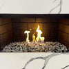 Modern indoor fireplace filled with American Fire Glass 1/2" Las Vegas pre-mixed reflective fire glass, featuring a shimmering blend of black, silver, and bronze pieces that enhance the dancing flames against sleek black brick and marble surroundings—perfect for luxury interiors, available at starfiredirecv.com.