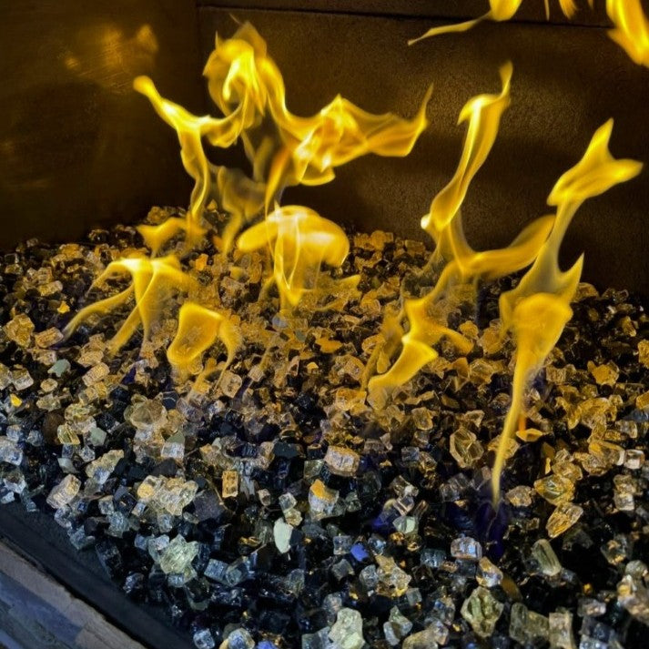 Close-up of glowing flames dancing over American Fire Glass 1/2" Las Vegas pre-mixed reflective fire glass, showcasing a luxurious blend of black, gold, and silver tones that sparkle with warmth—perfect for enhancing indoor fireplaces, available at starfiredirecv.com.