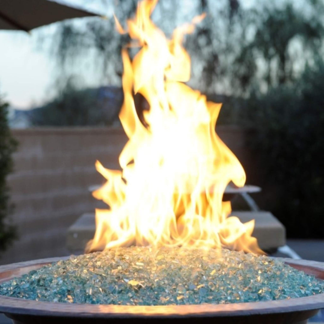 Close-up of vibrant flames rising from a copper fire bowl filled with American Fire Products 1/4" Non-Reflective Classic Fire Glass in light aqua, showcasing a clean, contemporary fire feature perfect for upscale outdoor spaces.