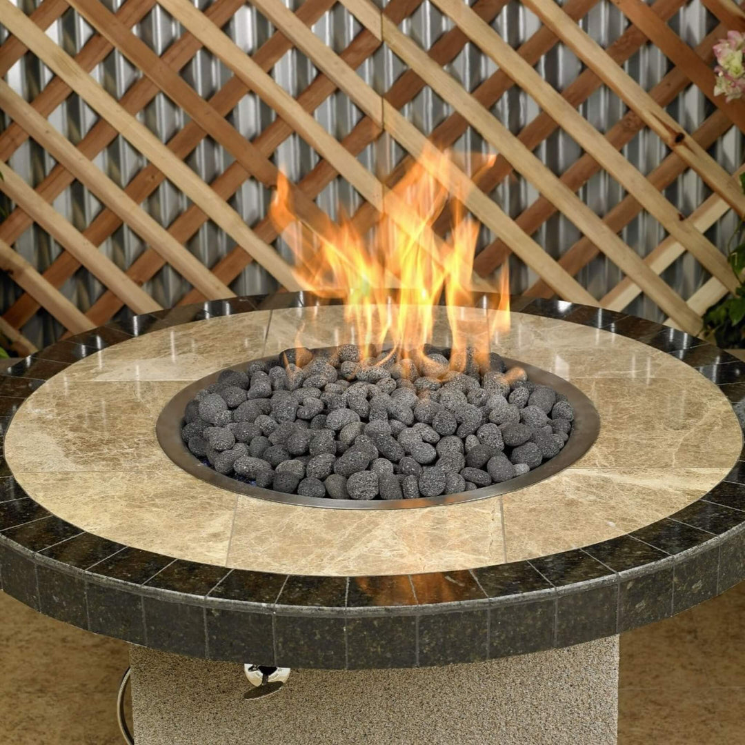 Close-up view of a round outdoor fire table with a polished stone top, filled with American Fire Products Small Gray Lava Stones, radiating warm flames and offering a sophisticated, natural focal point for backyard gatherings.