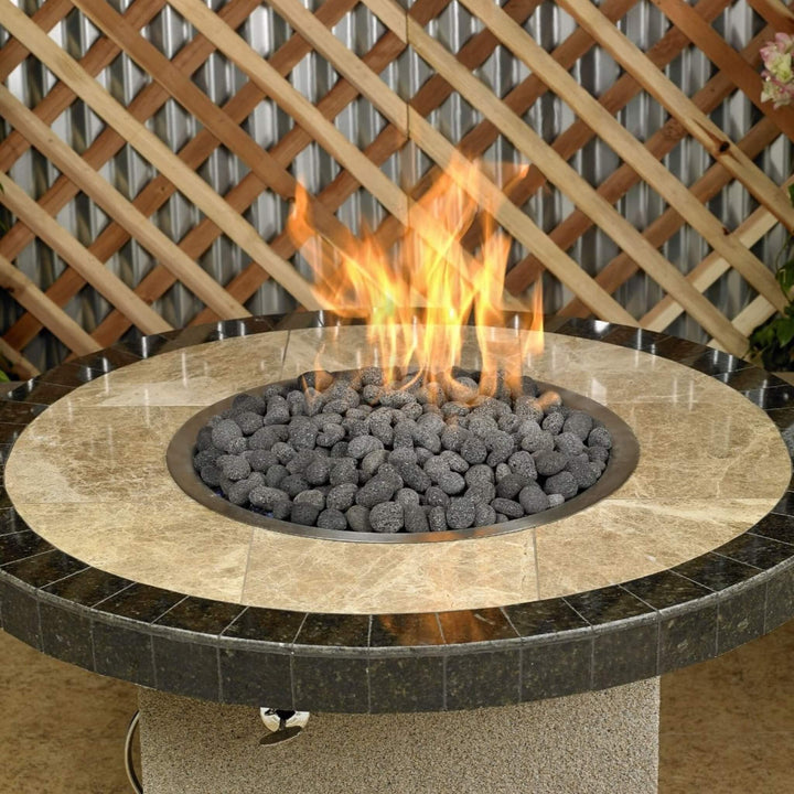 Close-up view of a round outdoor fire table with a polished stone top, filled with American Fire Products Small Gray Lava Stones, radiating warm flames and offering a sophisticated, natural focal point for backyard gatherings.