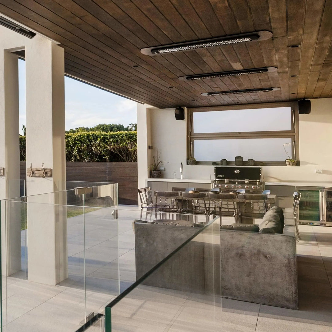 Sleek ceiling-mounted Bromic Tungsten Electric Smart-Heat Heaters recessed into a wood-paneled patio roof, efficiently warming an elegant outdoor dining and lounge area.