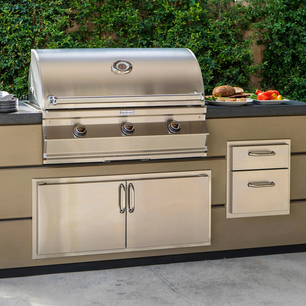 An outdoor kitchen setup focusing on the Fire Magic Select Reduced Height Double Access Doors underneath an enormous Fire Magic Grill.
