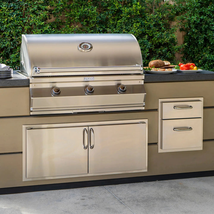 An outdoor kitchen setup focusing on the Fire Magic Select Reduced Height Double Access Doors underneath an enormous Fire Magic Grill.