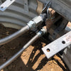 Close-up of a gas connection setup with corrugated stainless steel hoses securely attached to metal fittings in an outdoor fire pit installation, ensuring safe and durable gas supply