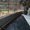 rchitectural indoor fire feature with interlinked stainless steel burners producing tall yellow flames beside a reflective water element, powered by the HPC Fire Inspired Linear Interlink Torpedo T-Burner.