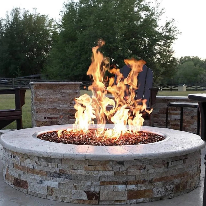 Rustic stone fire pit with a wide ledge and radiant copper fire glass, delivering high flames through an HPC Penta burner—ideal for luxurious outdoor ambiance.