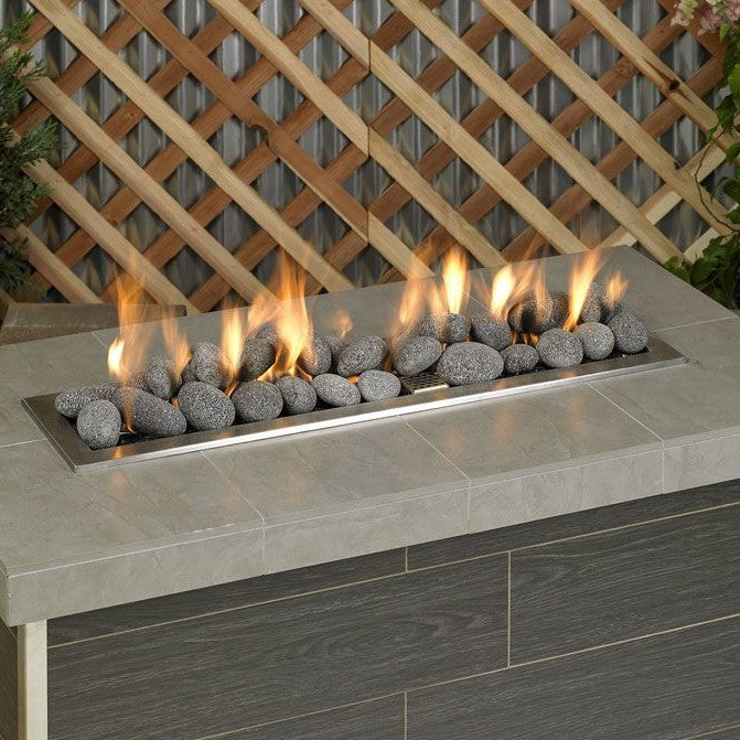Outdoor fire feature with American Fire Products gray lava stones, neatly arranged over a linear burner, creating a modern flame display perfect for patios or backyard gatherings.