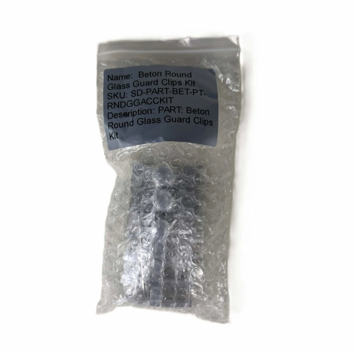 Factory-sealed Starfire Designs Béton Fire Pit Round Glass Wind Guard Clips Kit packaged in bubble wrap with product label and part description visible.