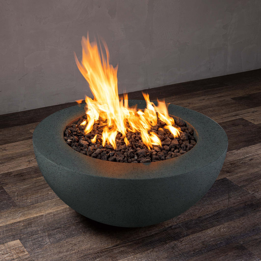 A side view of the Starfire Designs Gravity 36" Round Rustic Gravity Concrete (GFRC) Fire Pit - Propane Gas Hardline - Graphite with flames on, featuring sleek modern concrete bowl design and durable construction, perfect for outdoor patio spaces. Natural gas or propane compatible, enhancing warmth and ambiance. Lava rocks included for added aesthetic.
