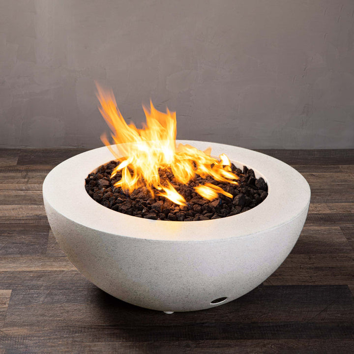 A side view of the Starfire Designs Gravity 36" Round Rustic Gravity Concrete (GFRC) Fire Pit - Propane Gas Hardline - White with flames on, featuring sleek modern concrete bowl design and durable construction, perfect for outdoor patio spaces. Natural gas or propane compatible, enhancing warmth and ambiance. Lava rocks included for added aesthetic.

