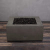 A side view of the Starfire Designs Gravity 36" Square Rustic Gravity Concrete (GFRC) Fire Pit - Propane Gas Hardline - Brown with flames on, featuring sleek modern concrete bowl design and durable construction, perfect for outdoor patio spaces. Natural gas or propane compatible, enhancing warmth and ambiance. Lava rocks included for added aesthetic.
