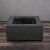 A side view of the Starfire Designs Gravity 36" Square Rustic Gravity Concrete (GFRC) Fire Pit - Propane Gas Hardline - Graphite with flames on, featuring sleek modern concrete bowl design and durable construction, perfect for outdoor patio spaces. Natural gas or propane compatible, enhancing warmth and ambiance. Lava rocks included for added aesthetic.

