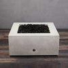A side view of the Starfire Designs Gravity 36" Square Rustic Gravity Concrete (GFRC) Fire Pit - Propane Gas Hardline - White with flames on, featuring sleek modern concrete bowl design and durable construction, perfect for outdoor patio spaces. Natural gas or propane compatible, enhancing warmth and ambiance. Lava rocks included for added aesthetic.
