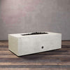A side view of the Starfire Designs Gravity 48" x 32" Rectangle Rustic Gravity Concrete (GFRC) Fire Pit - Propane Gas Hardline - White with flames on, featuring sleek modern concrete bowl design and durable construction, perfect for outdoor patio spaces. Natural gas or propane compatible, enhancing warmth and ambiance. Lava rocks included for added aesthetic.
