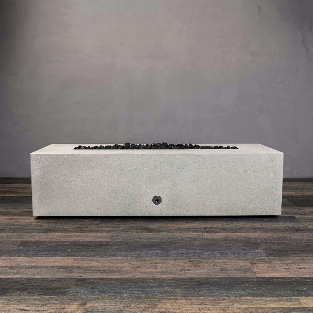 A side view of the Starfire Designs Gravity 60" x 32" Rectangle Rustic Gravity Concrete (GFRC) Fire Pit - Propane Gas Hardline - White with flames on, featuring sleek modern concrete bowl design and durable construction, perfect for outdoor patio spaces. Natural gas or propane compatible, enhancing warmth and ambiance. Lava rocks included for added aesthetic.
