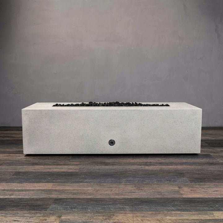 A side view of the Starfire Designs Gravity 60" x 32" Rectangle Rustic Gravity Concrete (GFRC) Fire Pit - Propane Gas Hardline - White with flames on, featuring sleek modern concrete bowl design and durable construction, perfect for outdoor patio spaces. Natural gas or propane compatible, enhancing warmth and ambiance. Lava rocks included for added aesthetic.
