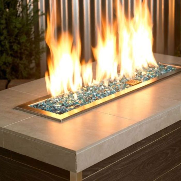 Vibrant blue flames dance above American Fire Products 1/4-inch Azuria reflective fire glass, elegantly set in a modern outdoor fire feature with a sleek brass trim.