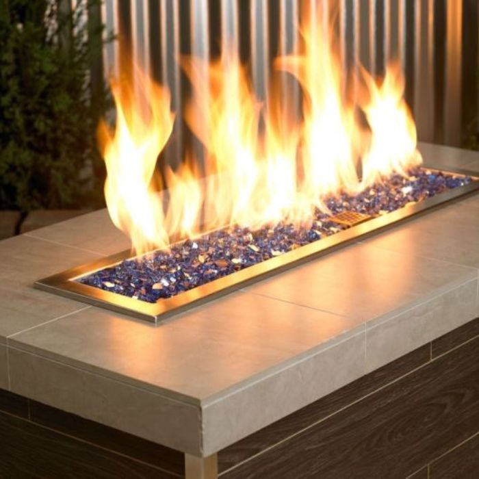 Modern linear fire feature showcasing American Fire Products 1/4" Cobalt Reflective Fire Glass, with vibrant blue tones sparkling beneath bold, golden flames—adding dynamic contrast and bold elegance to any outdoor space.