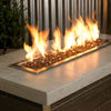 Warm copper-toned 1/4" reflective fire glass by American Fire Products showcased in a sleek linear fire feature, with golden flames dancing above the sparkling glass—perfect for adding rich, earthy elegance to any modern outdoor setting.