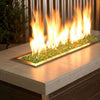 A sleek linear fire pit showcasing American Fire Products 1/4" Evergreen Reflective Fire Glass, where vibrant green glass pieces shimmer beneath tall golden flames—bringing a lush, earthy elegance to this contemporary outdoor centerpiece.