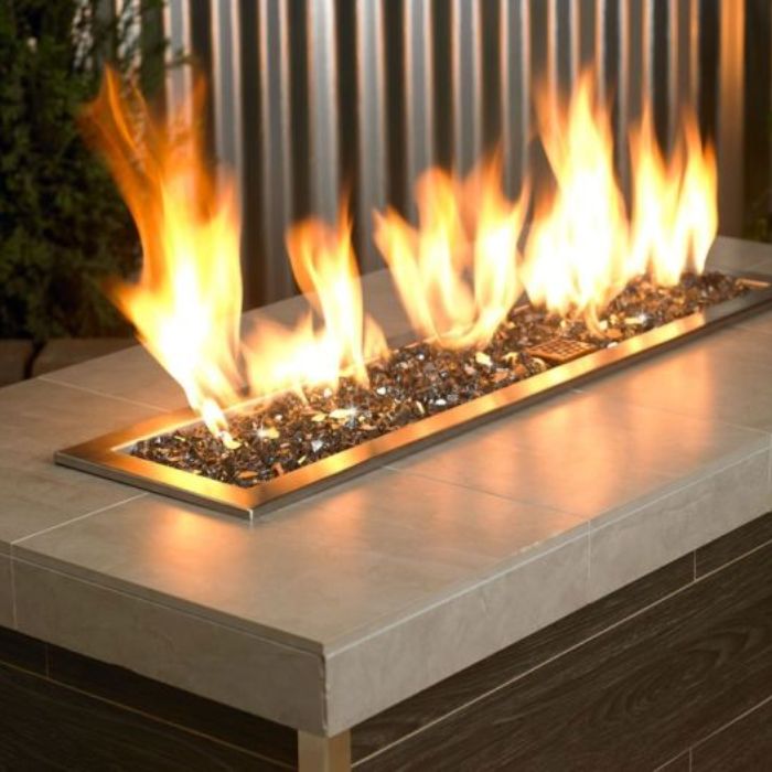 Contemporary fire feature showcasing bold, dancing flames over a bed of 1/4" Gray Reflective Fire Glass by American Fire Products—adding a sleek, modern shimmer and cozy ambiance to this tiled outdoor fire table.