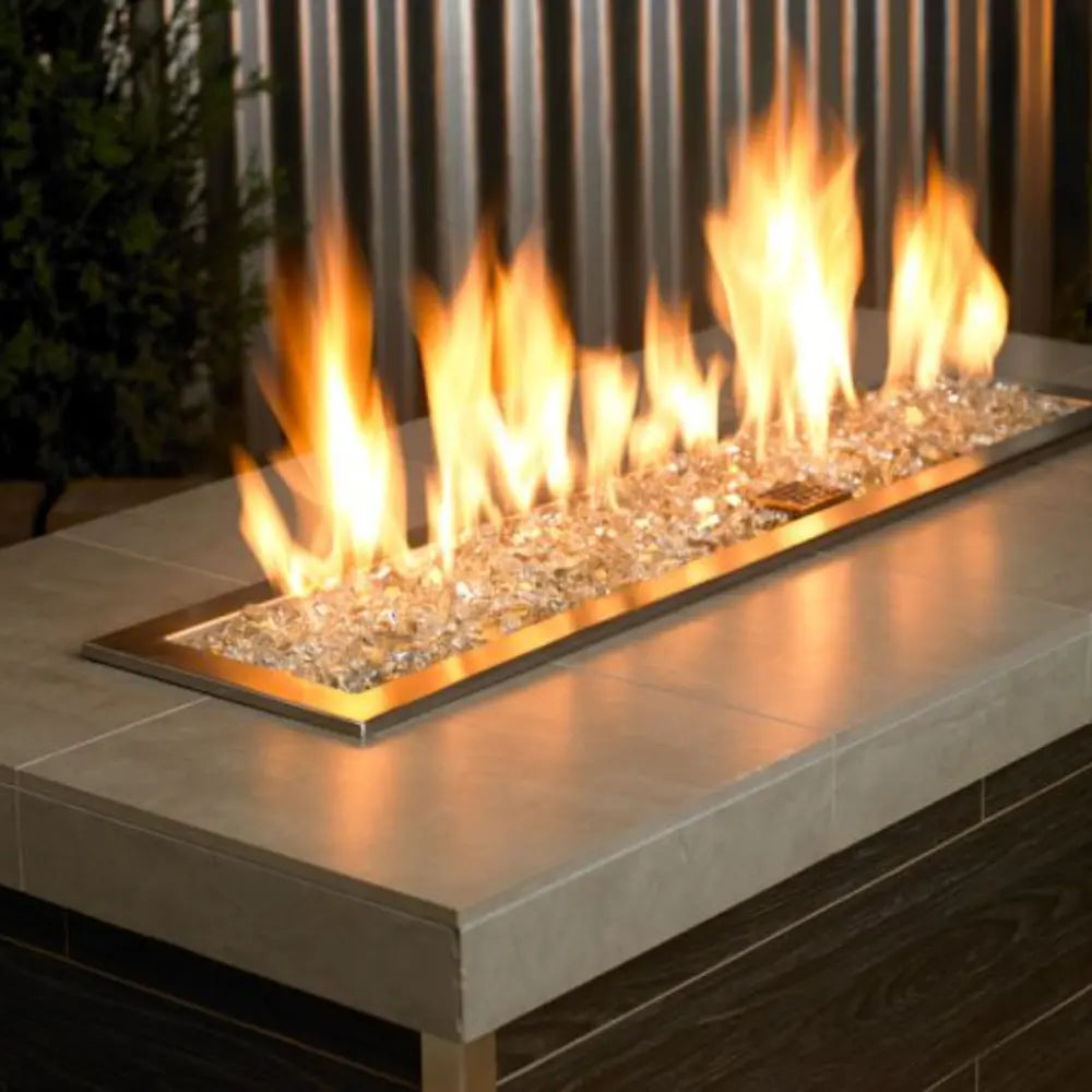 1/4" Platinum Reflective Fire Glass by American Fire Products glowing beneath a bold, elegant flame in a modern fire pit—its crystal-clear shards and mirrored finish create a dazzling sparkle, adding contemporary flair and radiant ambiance to any outdoor setting.