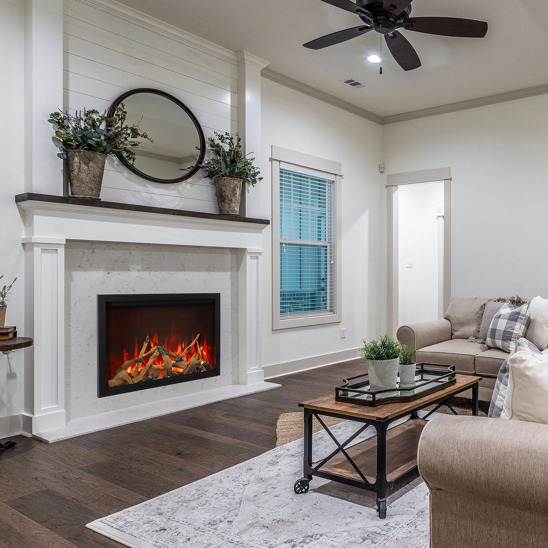 The Amantii Traditional Bespoke Smart Electric Fireplace set within a rustic fireplace mantle in a farmhouse-style living room. With natural wood accents and vibrant flames, it delivers an authentic aesthetic and modern heating convenience.