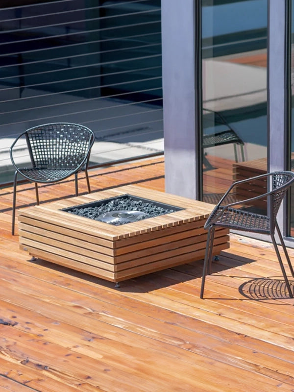 Modern outdoor seating area with a square wooden slatted fire pit on a wooden deck, paired with minimalist metal chairs, creating a serene and contemporary outdoor relaxation space