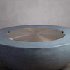 Starfire Designs Beton Round Stainless Steel Burner Cover placed on a round fire pit, showcasing a sleek and polished stainless steel finish