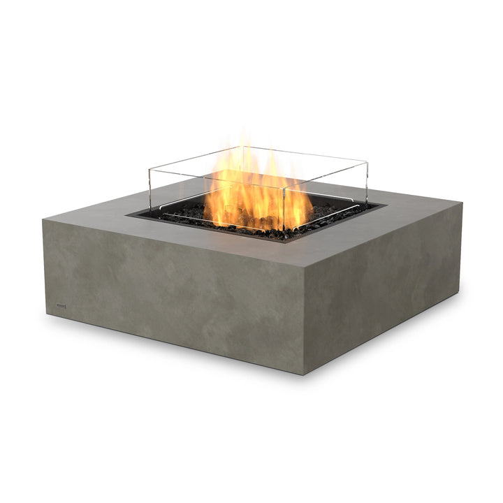 The EcoSmart Fire Base 40 Natural outdoor fire pit features a propane burner with a sleek tempered glass wind guard for enhanced safety and wind resistance. This square fire pit table is perfect for patio entertaining, offering a stylish and smokeless fire solution for any modern backyard or outdoor space.