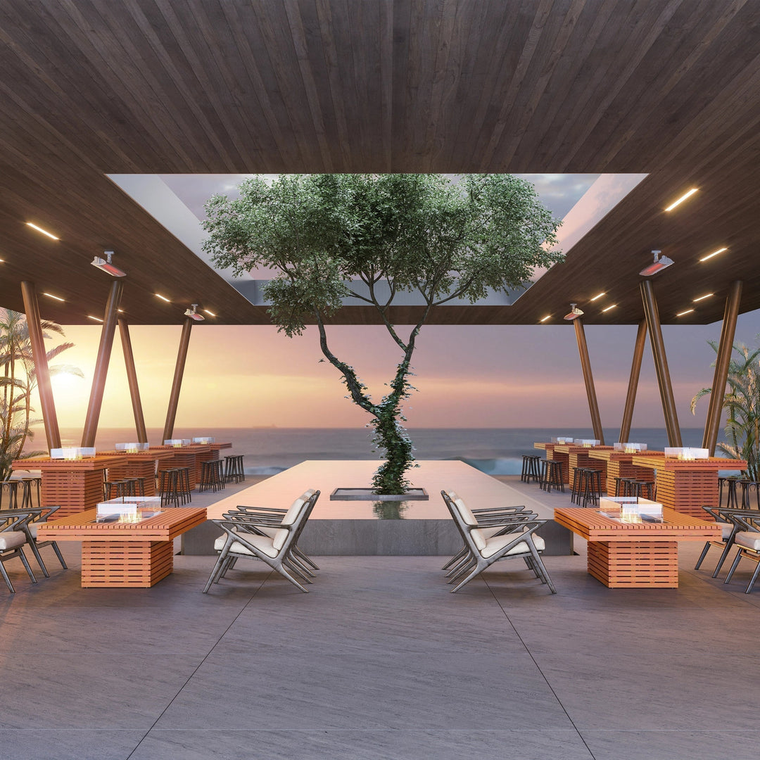 The EcoSmart Fire Gin 90 Chat Height fire pit table seamlessly integrates into an upscale beachfront restaurant with an open-air dining setup, offering a stunning view of the ocean and sunset. The rectangular fire pit provides an elegant and cozy atmosphere for guests, with a long burner design that produces a clean-burning, natural flame. Perfect for luxury resorts, outdoor patios, and modern dining spaces.