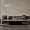 A sleek and contemporary EcoSmart Fire Gin 90 Low fire pit table in a sophisticated indoor lounge setting. Its matte black finish seamlessly integrates with modern gray sectionals, creating an elegant ambiance. The long rectangular fire pit burner is stylish and functional, offering a clean-burning gas fire feature for luxury indoor spaces.