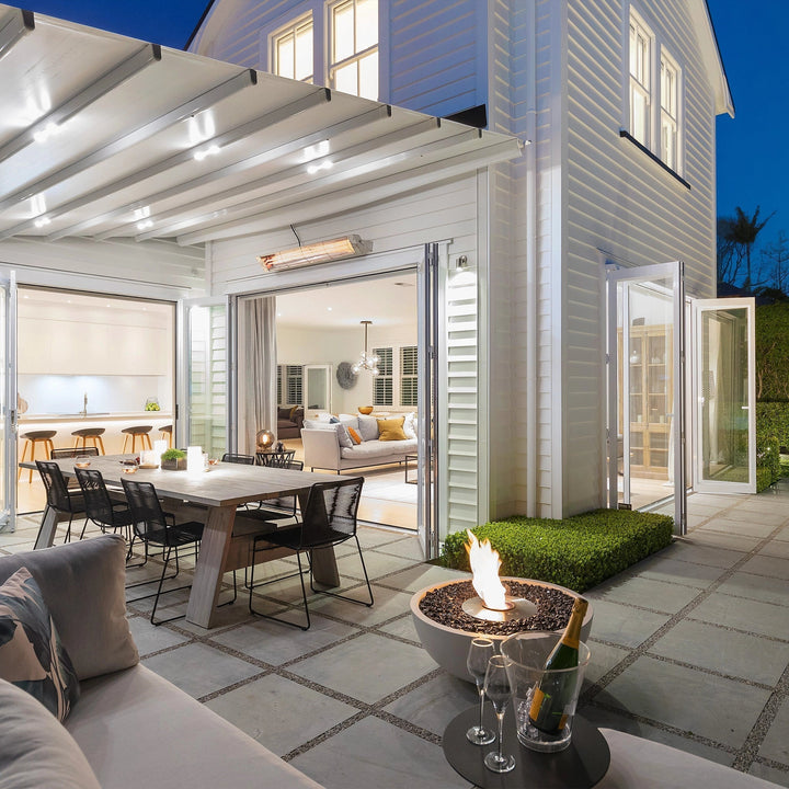 A stylish EcoSmart Fire Mix 850 bone fire pit with a stainless steel burner, placed on a modern outdoor patio. The sleek, bowl-shaped fire pit is filled with black fire glass, producing a warm, inviting flame. This luxury fire pit is ideal for outdoor gatherings, adding a contemporary ambiance to high-end patios and backyards.